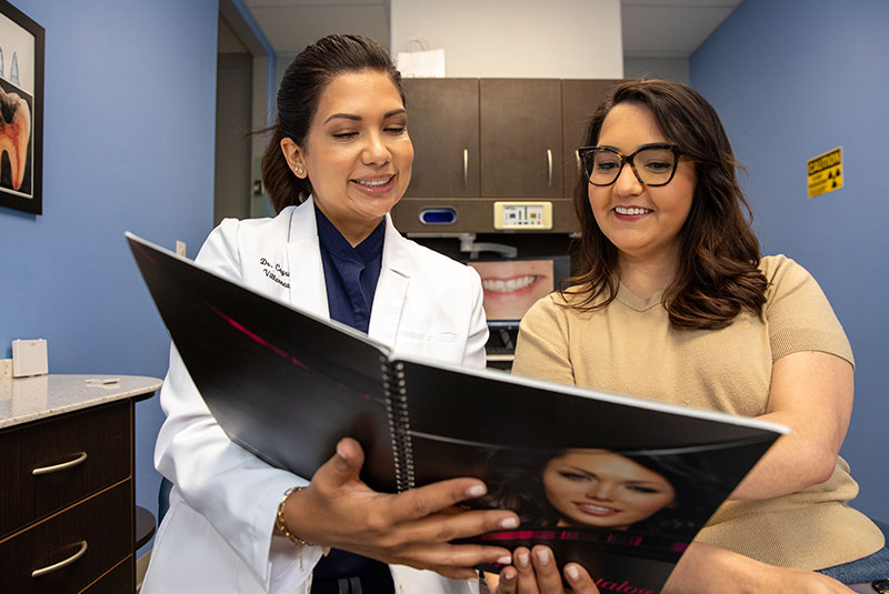 doctor and patient going over a veneer service treatment book for patient's procedure